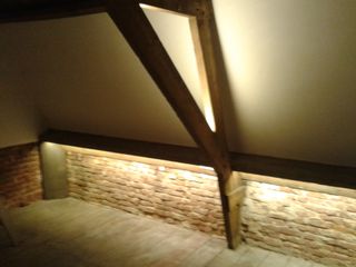 Hobbyzolder met LED-verlichting langs de bakstenen muur onder het schuine dak