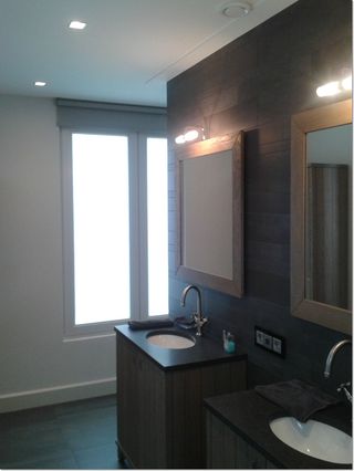 Badkamer met donkere wandbekleding, spiegels met verlichting en een wastafelmeubel