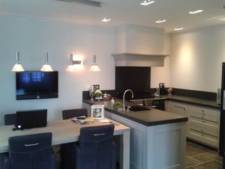 Woonkeuken met hanglampen boven de tafel en inbouwspots in het plafond